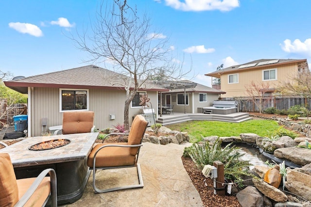 rear view of house featuring roof with shingles, a hot tub, an outdoor fire pit, a patio area, and fence