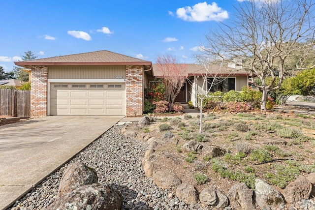 ranch-style home with a garage, driveway, brick siding, and fence