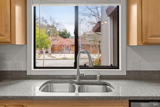 kitchen featuring dishwasher, a sink, and light brown cabinets