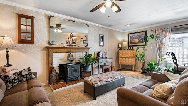 living area featuring ornamental molding, a wood stove, ceiling fan, baseboards, and wallpapered walls