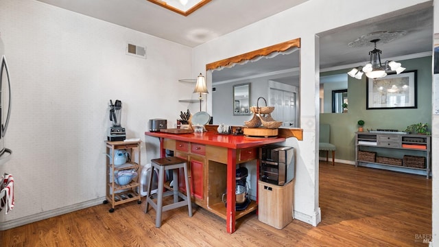 bar with crown molding, visible vents, a chandelier, and wood finished floors