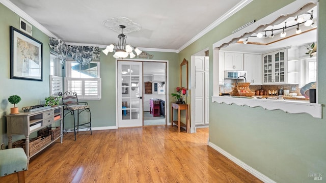 dining room with light wood-style flooring, visible vents, baseboards, ornamental molding, and an inviting chandelier