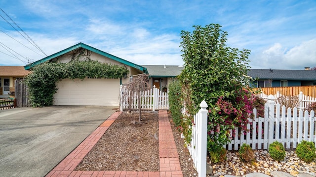 view of front of home featuring a fenced front yard, concrete driveway, and a garage