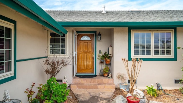 property entrance featuring a shingled roof and stucco siding