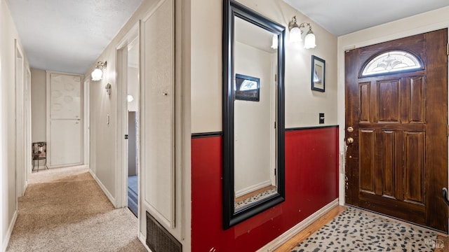 foyer featuring carpet and baseboards