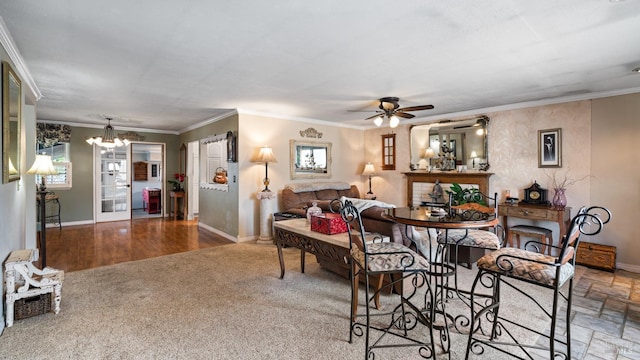 dining area with ceiling fan with notable chandelier, stone finish flooring, ornamental molding, and baseboards