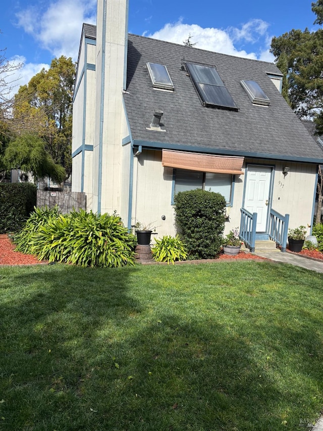 rear view of house featuring a shingled roof and a yard