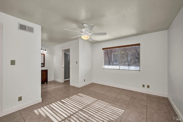 spare room with light tile patterned floors, baseboards, visible vents, and a ceiling fan