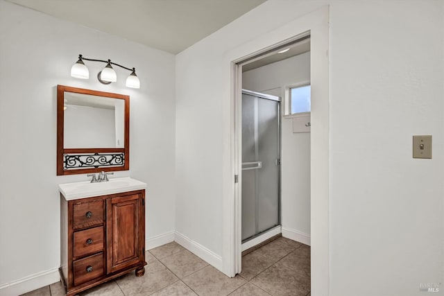 bathroom with a stall shower, vanity, baseboards, and tile patterned floors