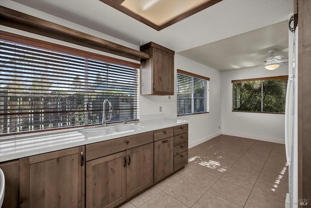 kitchen featuring light tile patterned floors, light countertops, a sink, and ceiling fan