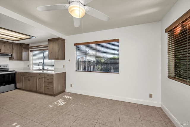 kitchen with light countertops, under cabinet range hood, stainless steel electric range, and light tile patterned floors