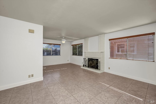 unfurnished living room with ceiling fan, light tile patterned floors, a fireplace, and baseboards