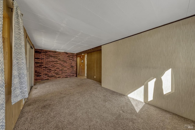 empty room featuring brick wall, wood walls, and carpet flooring