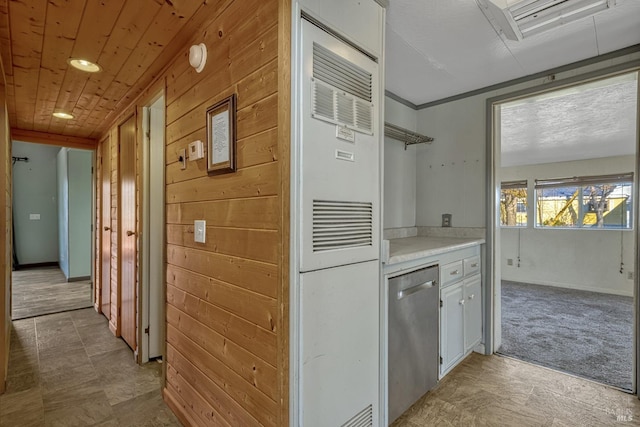 kitchen with wooden ceiling, light countertops, stainless steel dishwasher, and wood walls