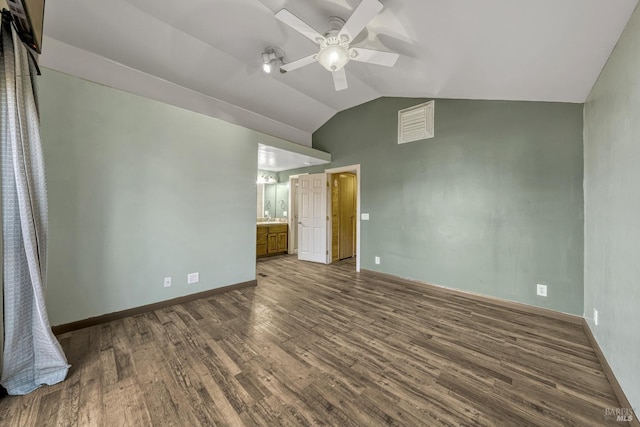 unfurnished bedroom with dark wood finished floors, a ceiling fan, vaulted ceiling, baseboards, and ensuite bath