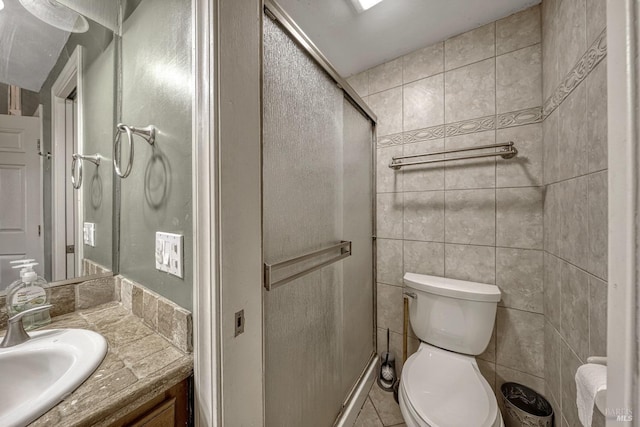 full bathroom with a stall shower, tile walls, vanity, and toilet