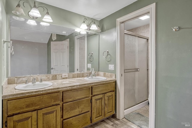 bathroom with wood finished floors, a sink, a shower stall, and double vanity