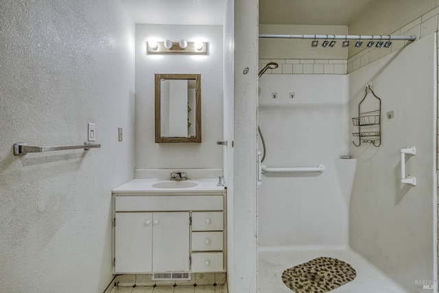 bathroom featuring visible vents, a shower, and vanity