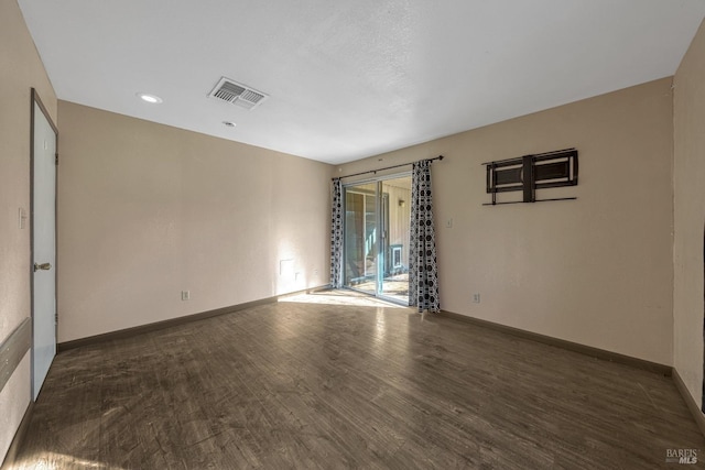 empty room with wood finished floors, visible vents, and baseboards