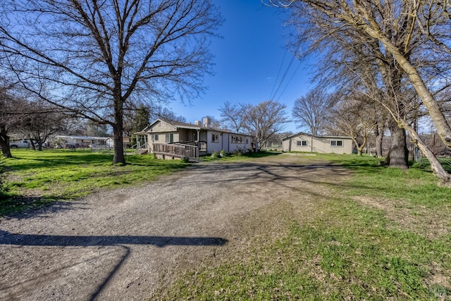 view of front of house featuring driveway, a wooden deck, and a front lawn