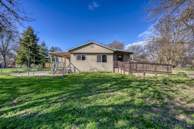 rear view of house featuring a lawn and fence