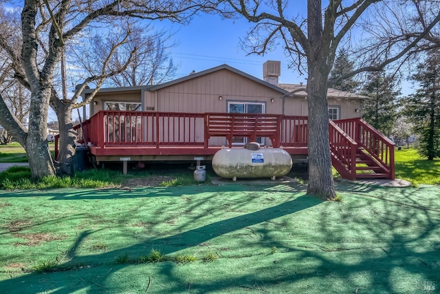 back of house with a chimney, a deck, and a yard