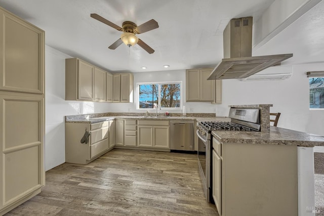 kitchen with stainless steel appliances, a sink, island exhaust hood, and cream cabinets