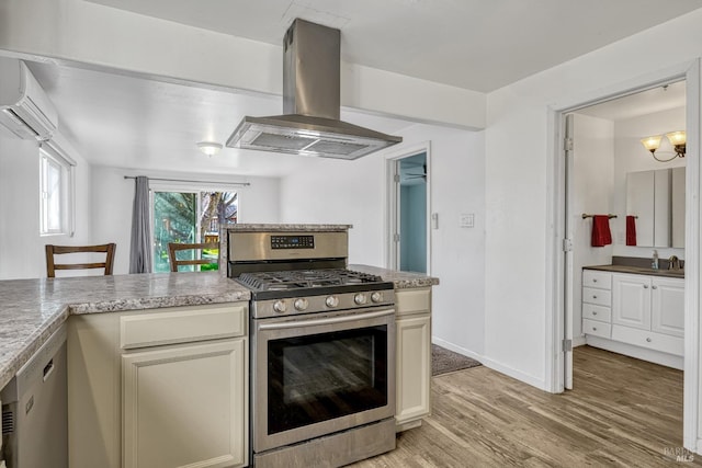 kitchen with light wood finished floors, a wall mounted AC, appliances with stainless steel finishes, a sink, and island range hood