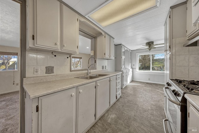 kitchen featuring a wealth of natural light, light countertops, a sink, and gas range