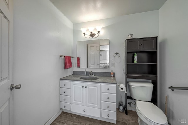 bathroom featuring toilet, baseboards, wood finished floors, and vanity