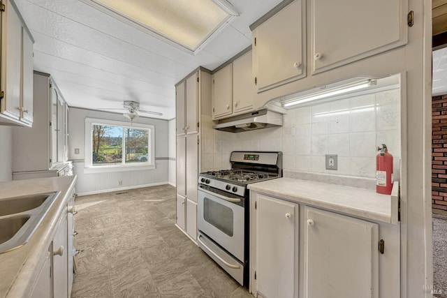 kitchen featuring stainless steel range with gas cooktop, light countertops, ceiling fan, a sink, and under cabinet range hood