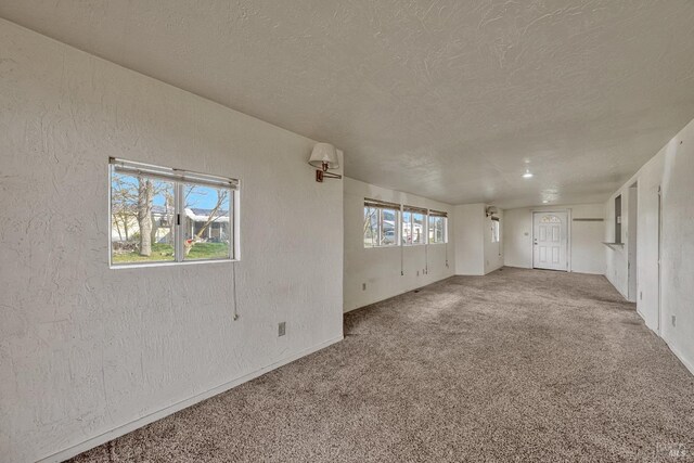 unfurnished room with carpet floors, a textured ceiling, and a textured wall