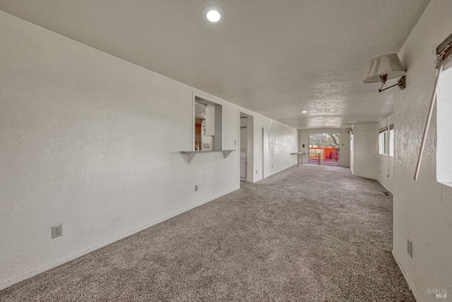 unfurnished room featuring a textured ceiling, a textured wall, and carpet flooring