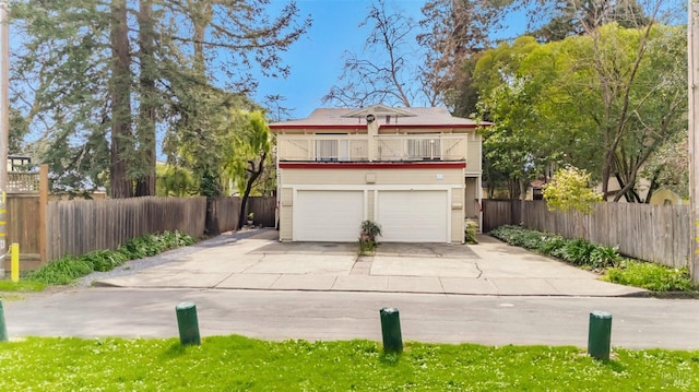 view of front of home with a garage, fence, and a balcony