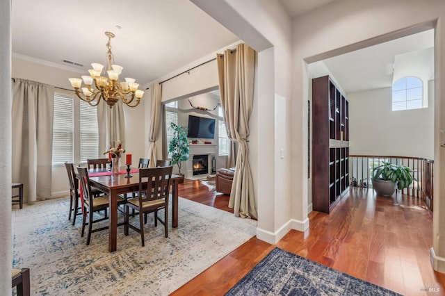 dining space with plenty of natural light, a lit fireplace, and wood finished floors