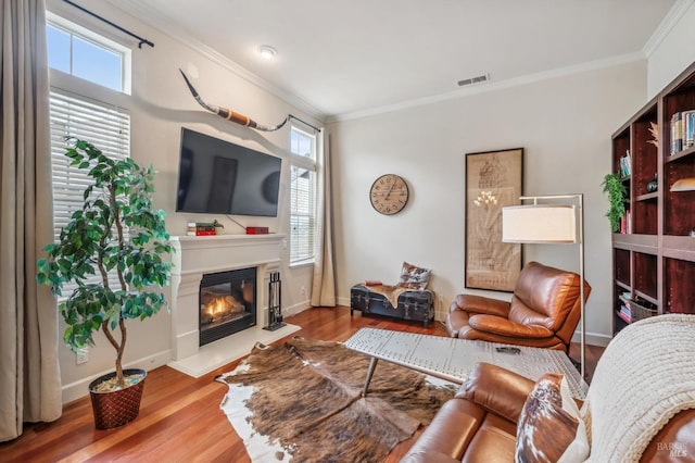 living area featuring a glass covered fireplace, plenty of natural light, wood finished floors, and visible vents