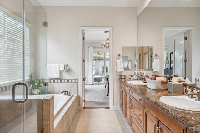 full bathroom featuring double vanity, tile patterned floors, a garden tub, an inviting chandelier, and a sink