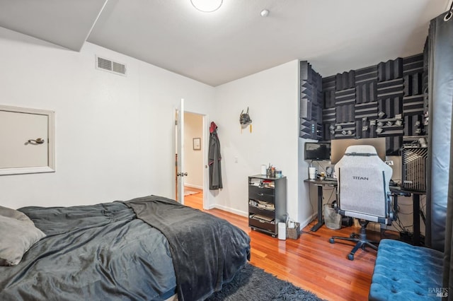 bedroom featuring baseboards, visible vents, and wood finished floors