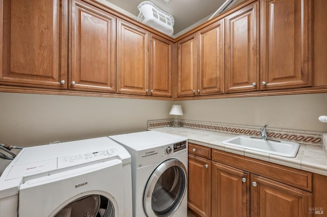 laundry area with cabinet space, washing machine and dryer, and a sink