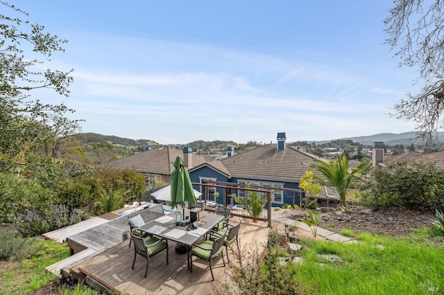 rear view of property featuring a deck with mountain view and outdoor dining area