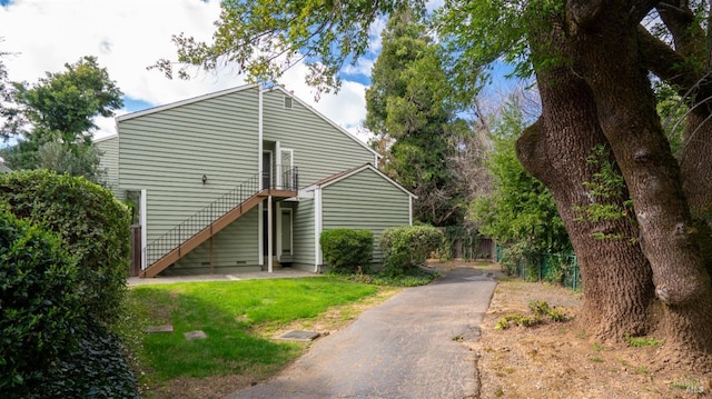 view of home's exterior featuring fence, stairway, and a lawn