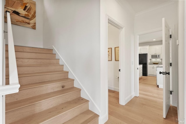 stairs featuring ornamental molding, wood finished floors, and baseboards