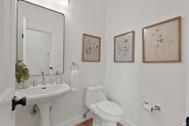 half bath featuring baseboards, toilet, and wood finished floors