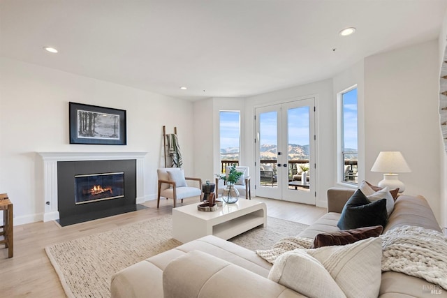 living room featuring light wood-type flooring, a fireplace with flush hearth, and recessed lighting