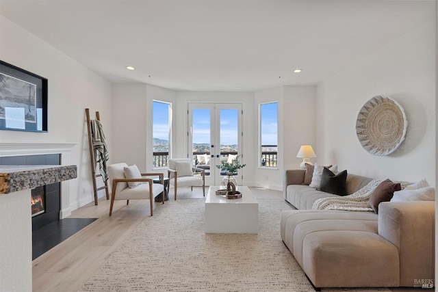 living room featuring recessed lighting, french doors, a tiled fireplace, and wood finished floors