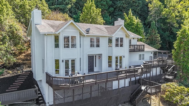 view of front of property featuring stairway, french doors, a chimney, and a view of trees