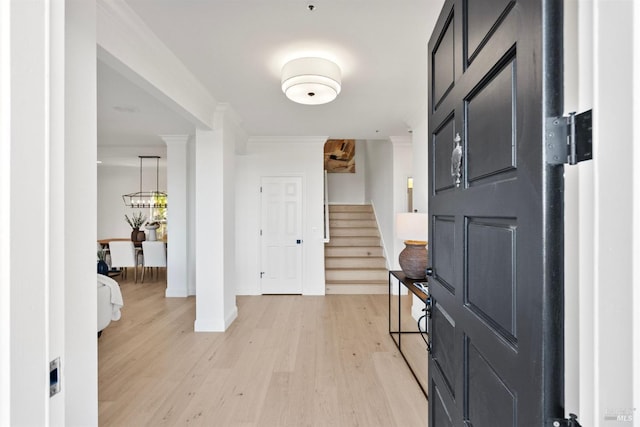 foyer with ornamental molding, baseboards, light wood finished floors, and stairs