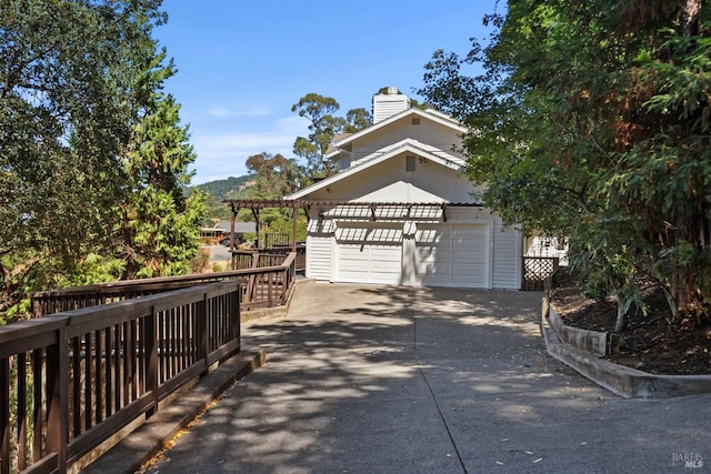 exterior space featuring a garage, driveway, and a chimney