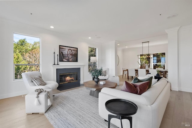 living area featuring baseboards, recessed lighting, a fireplace with flush hearth, and light wood-style floors