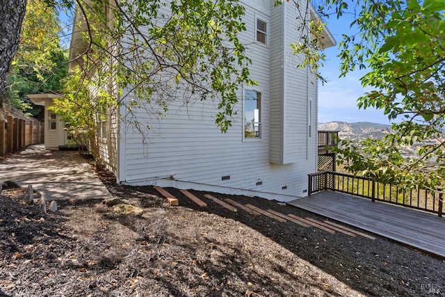 view of home's exterior featuring crawl space, a deck with mountain view, and fence